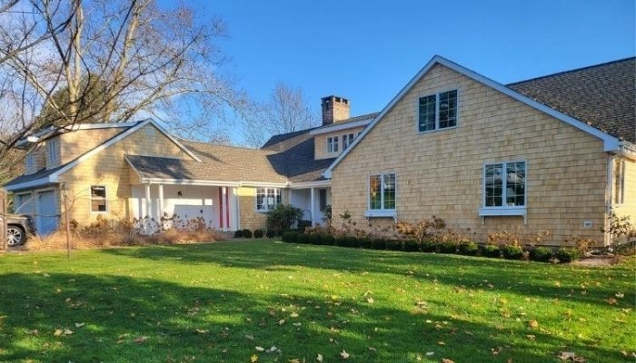A residence with an expansive yard and driveway, focusing on eco-friendly siding materials: cedar and vinyl options.