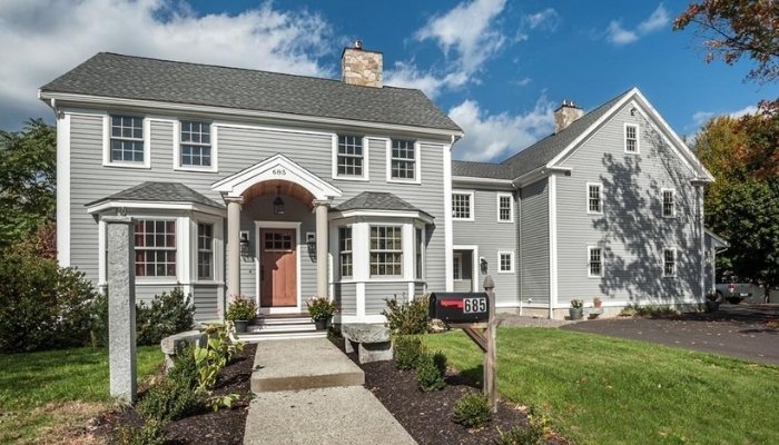 A gray house with a porch and yard, representing the comparison of energy savings and insulation for cedar and vinyl siding.