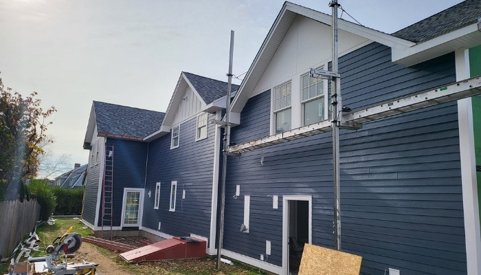 A house with blue siding is being construct, highlighting the importance of installation quality in siding choices.