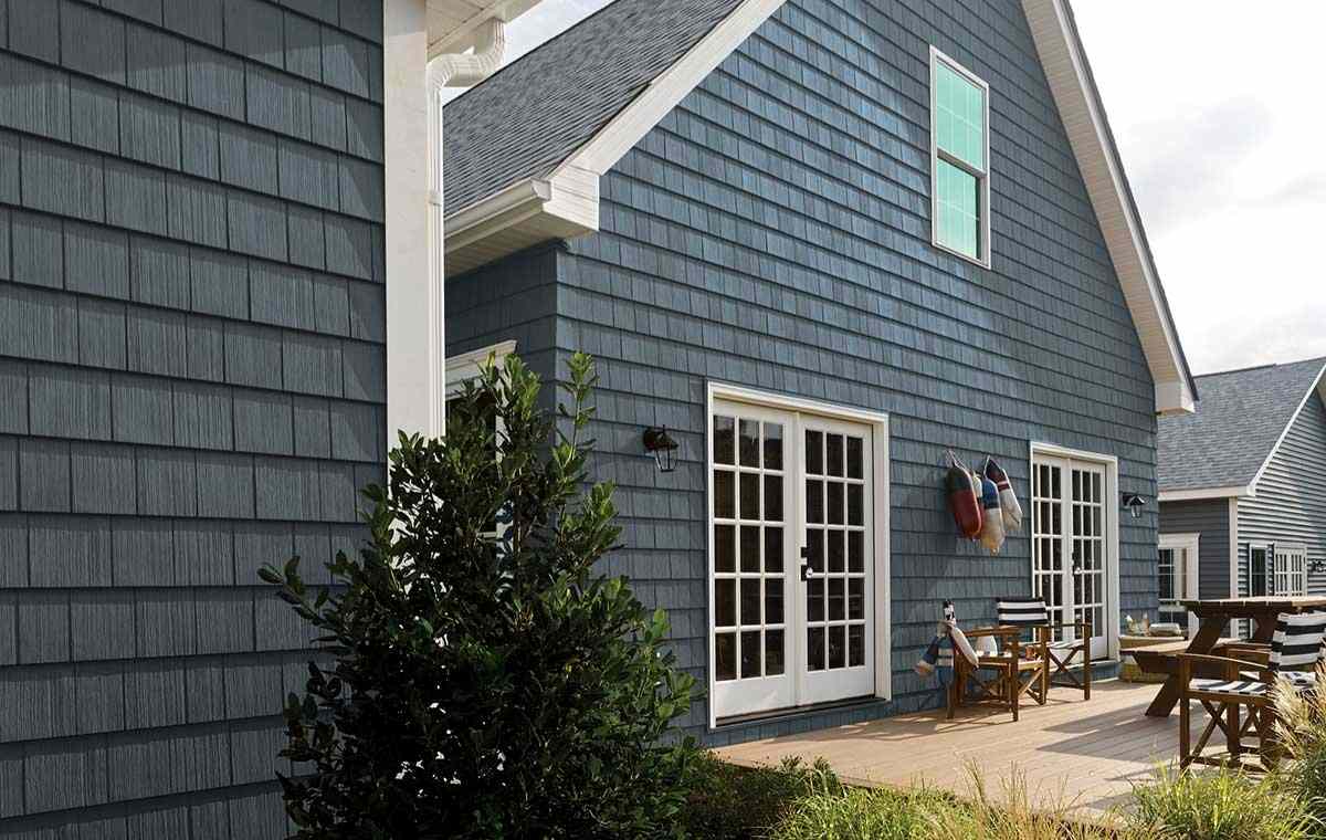A blue house with a patio set, emphasizing fiber cement siding, located in Fairfield, CT.