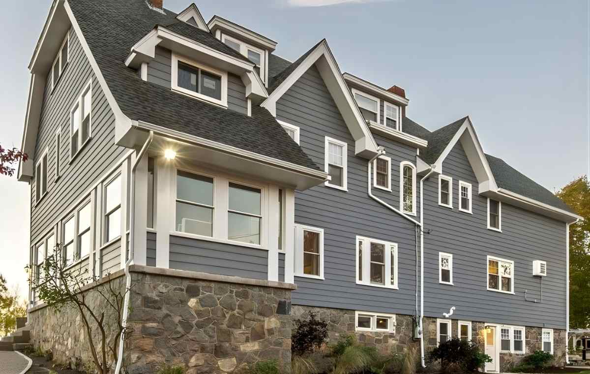 A spacious gray house featuring a stone wall, representing Hardie Board siding in Greenwich, CT.