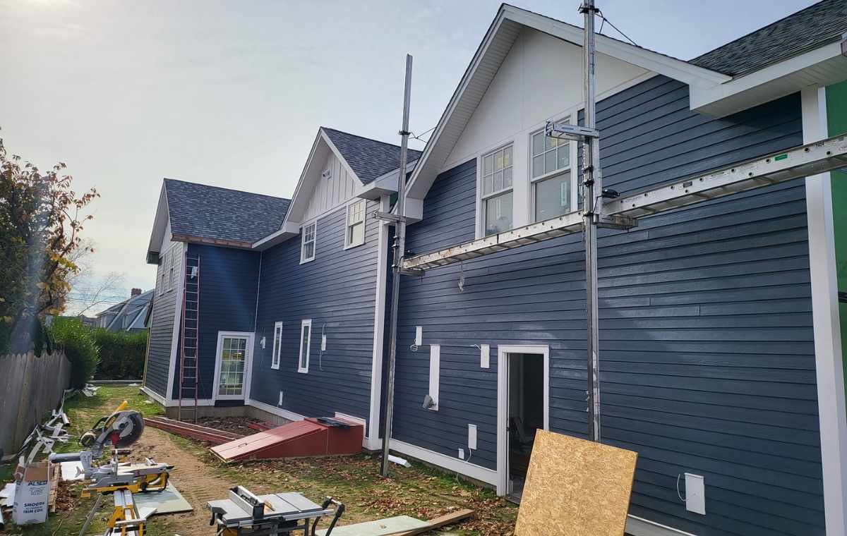 Dark blue house exterior with white trim under construction, featuring scaffolding and saws.