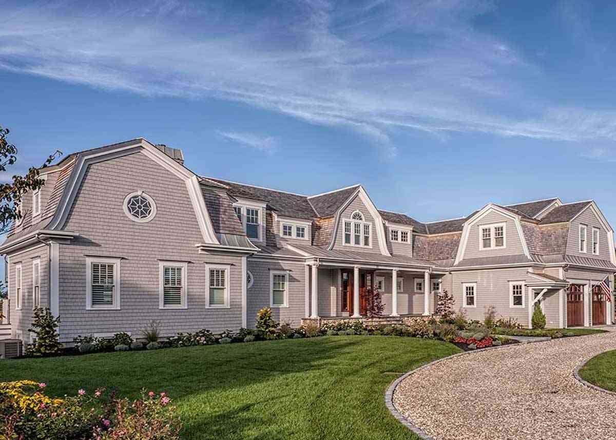 Gray gambrel shingle home with driveway.