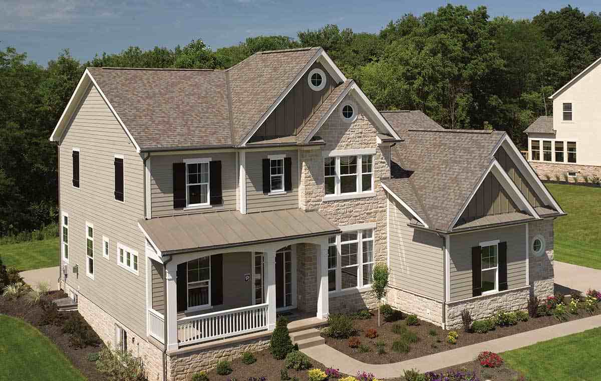 Exterior of a two-story home with tan siding, stone accents, and gray roof.