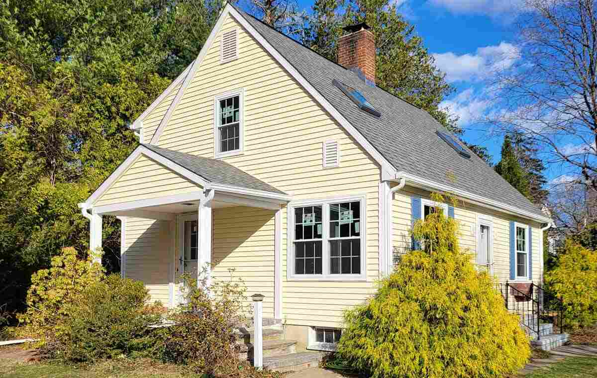 Cape Cod home with yellow siding, gray roof, and blue shutters.