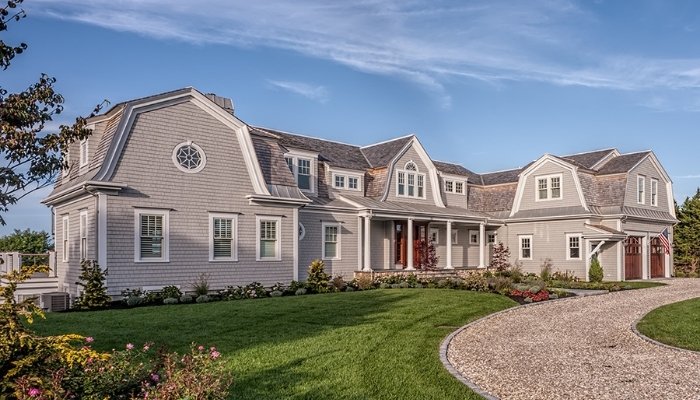 A prominent residence with a driveway, illustrating cedar siding, discussing its lifespan in comparison to other styles.