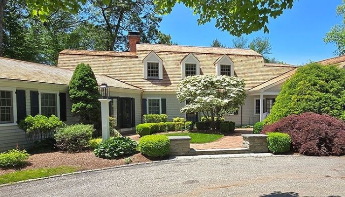 A spacious house with a driveway and lush trees, representing a typical suburban landscape.
