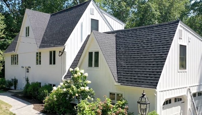 A white house topped with black shingles, illustrating the possibilities of aluminum and steel siding renovations.