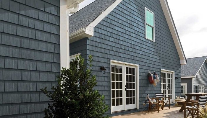 A blue house with a deck and patio, demonstrating the cost-effective fiber cement siding upgrade.