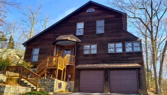 A spacious brown house with a garage and stairs, showcasing recently installed wood clapboard siding.