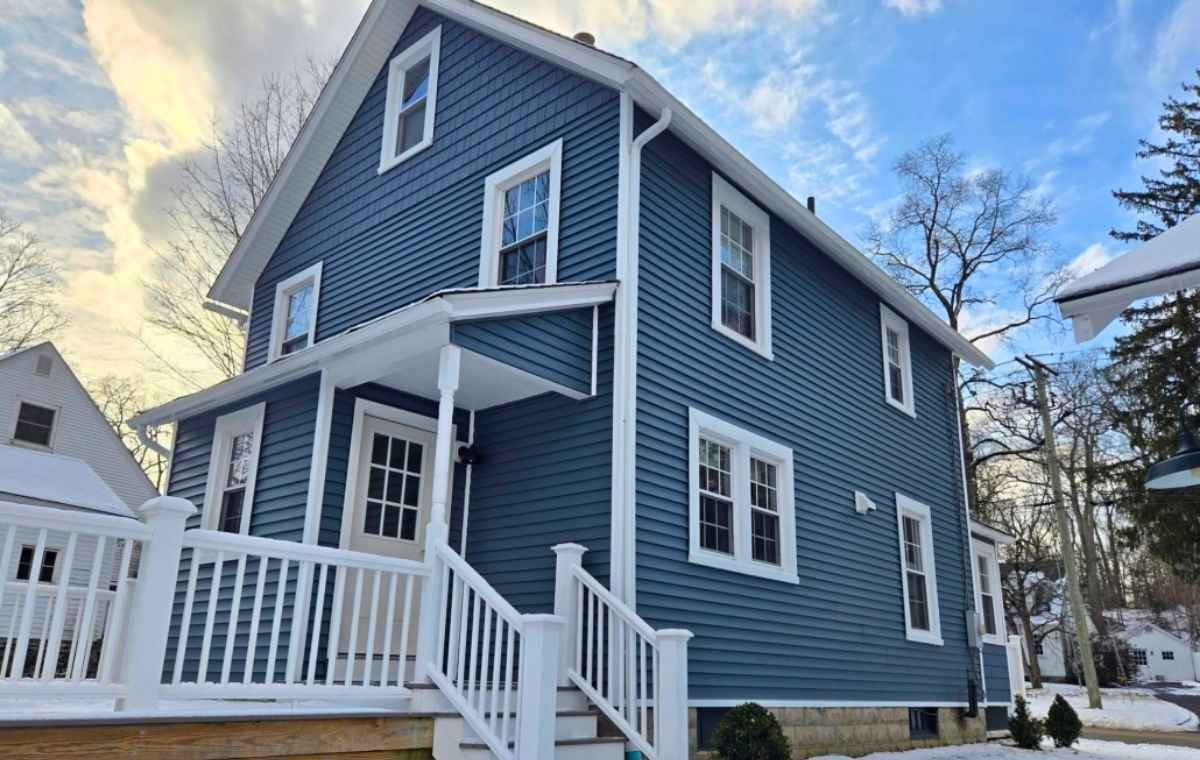 A blue house with white trim and a white porch, representing the work of vinyl siding contractors based in Connecticut.