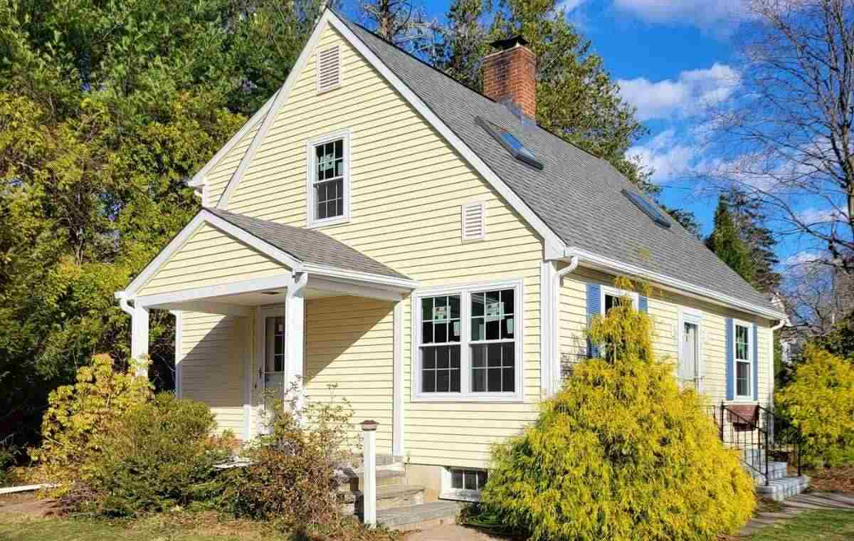 A yellow house featuring white trim and a black roof, representing vinyl siding services in Fairfield, CT.