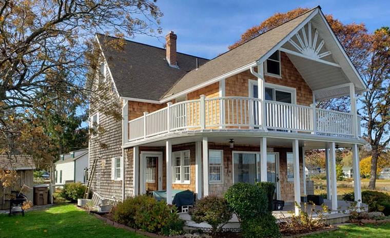 A house with a spacious porch and balcony, complete with elegant decking and a picturesque setting.