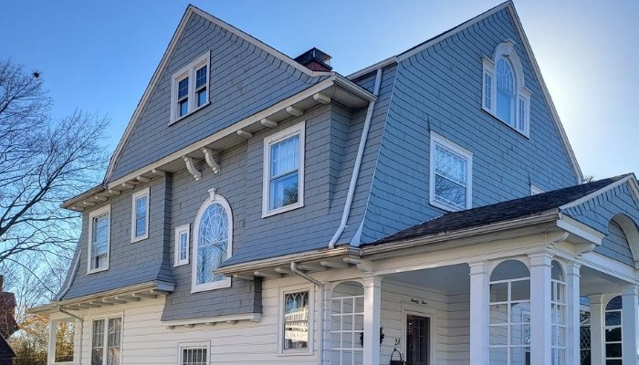 Wood siding repair on blue shingle home with visible cracks, holes, and minor surface damage