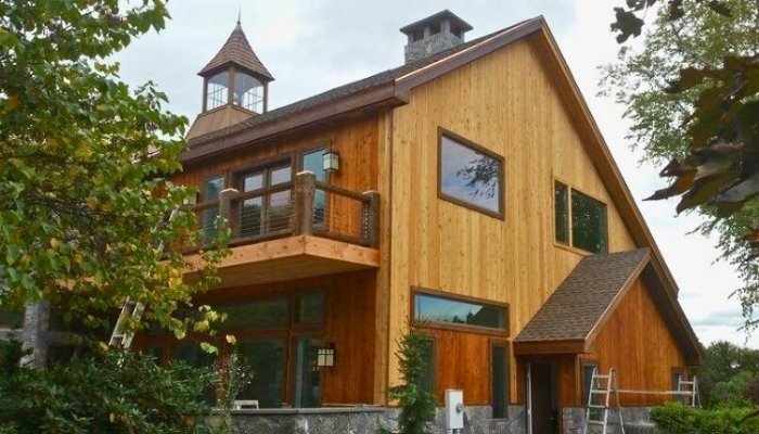 Repair rotten wood siding on modern cedar home with balcony and exterior ladder