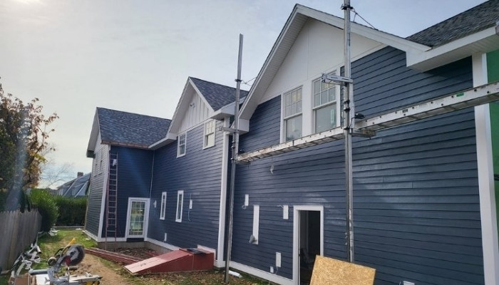 Wood siding installation on blue home with scaffolding and tools in Pine Orchard CT