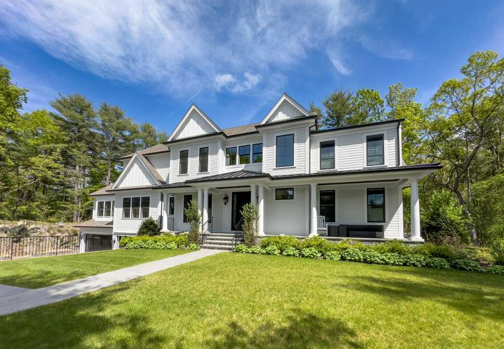 Modern white two-story house with black window trim, a front porch, and a green lawn.