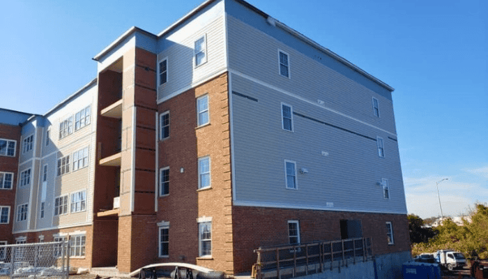 Multi-story building under construction with grey siding and brick.