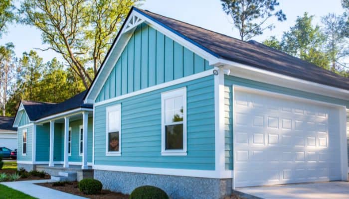 Bright turquoise one-story home with white trim, a double garage, and matching siding.