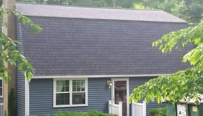 House with blue siding and a dark grey gambrel roof.