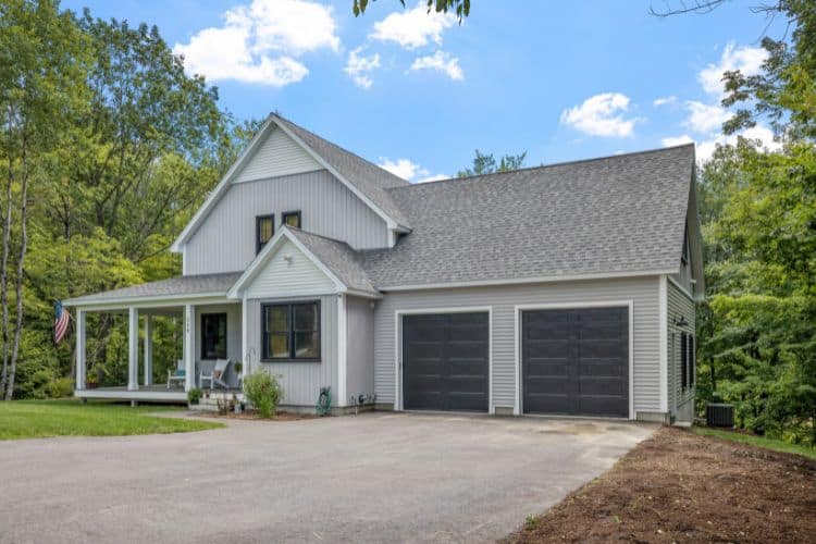 Two-story light gray house with a covered front porch and a two-car garage.