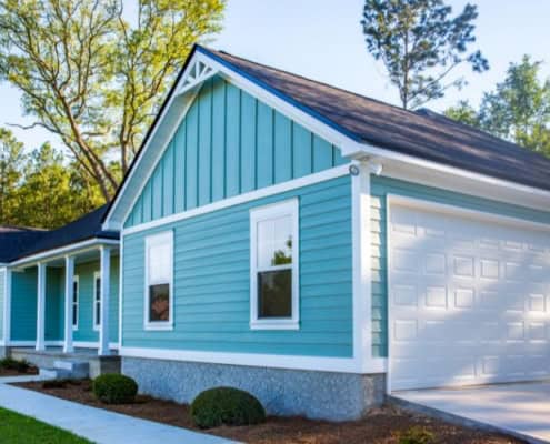 Single-story turquoise house with white trim, a front porch, and a white garage door.