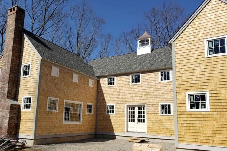 Light cedar shingle siding on a two-story home exterior with white window frames and trim.