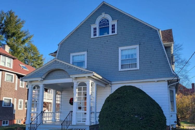 Blue shingle siding on upper floor and white horizontal siding on main level of home.